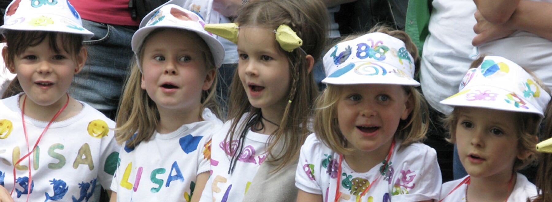Fünf Kinder sitzend mit bunten T-Shirts