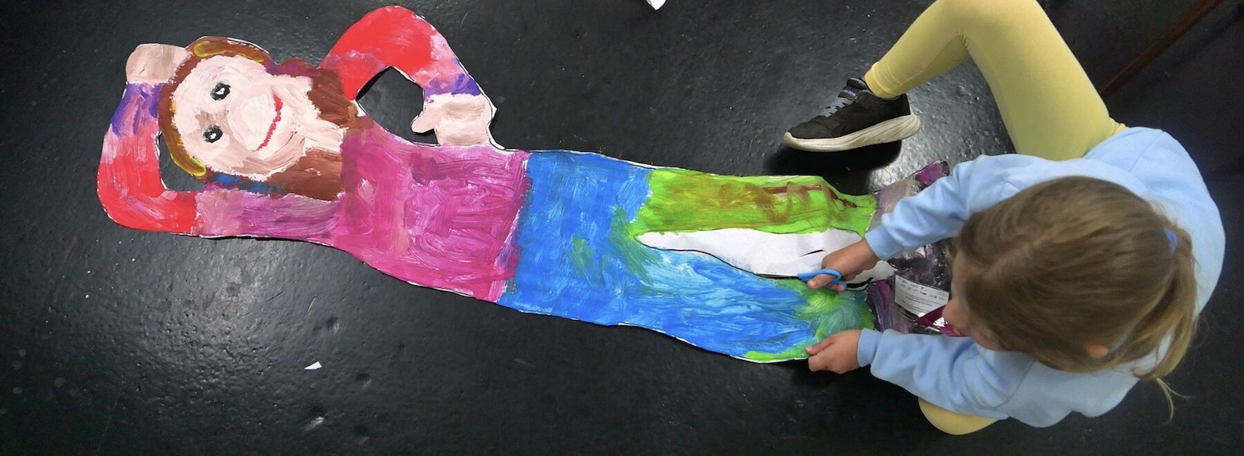 Ein Kind bearbeitet am Boden eine Kunstfigur