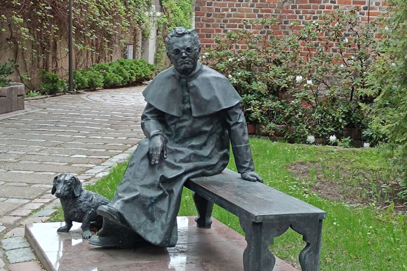 Eine Statue als Mann sitzend auf einer Bank mit einem Hund