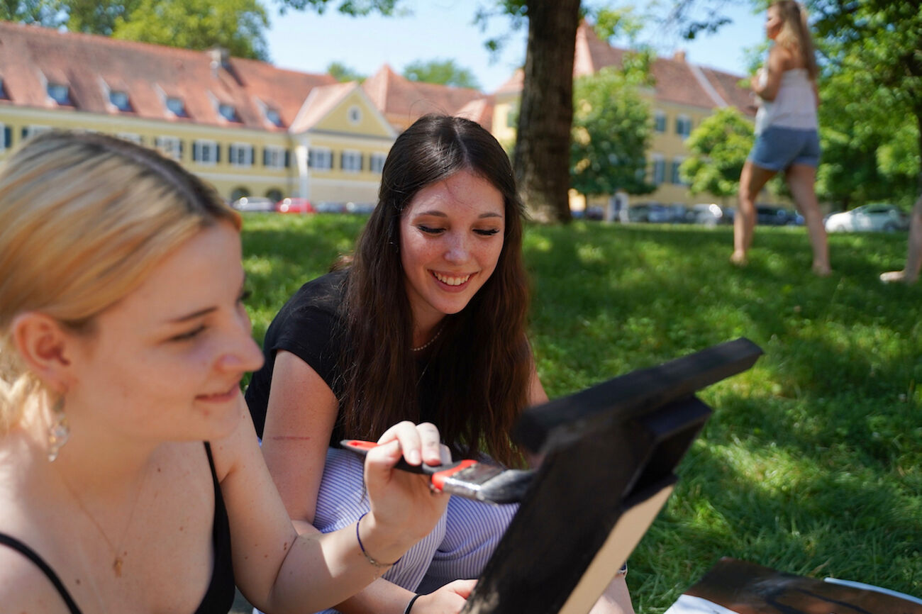 2 Studierende malen in der Wiese