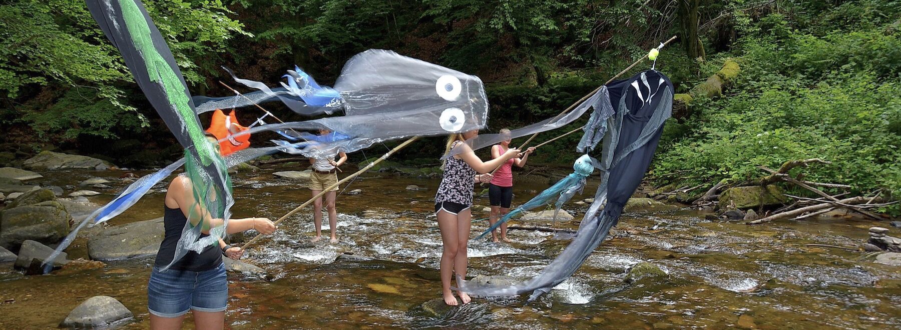 Studierende lassen in einem Bach Drachen fliegen