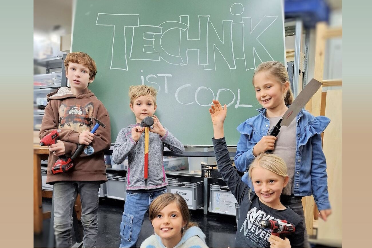 Kinder im Werkraum vor einer Tafel mit der Aufschrift "Technik ist cool"