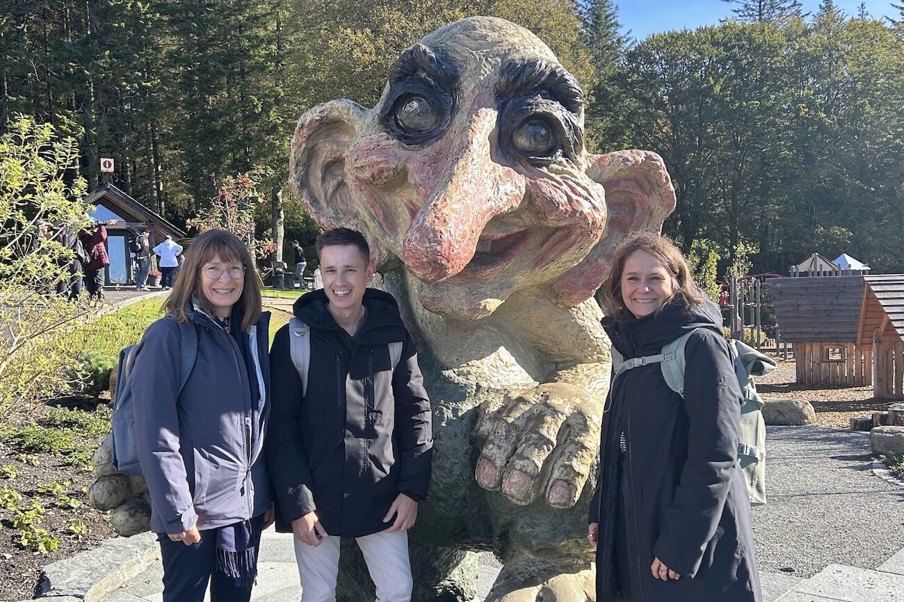 Drei Lehrende in Bergen (Outdoor) vor einer Figur