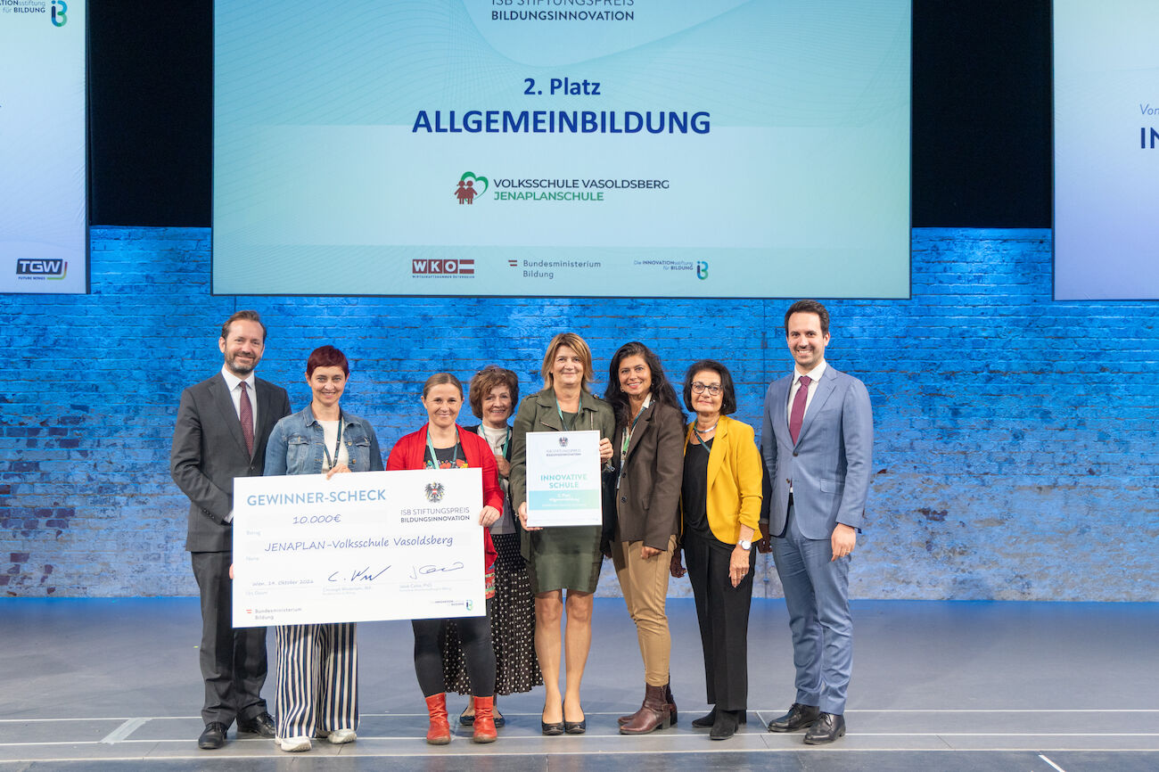 Gruppenbild: Preisverleihung auf dem Podium der Veranstaltungshalle