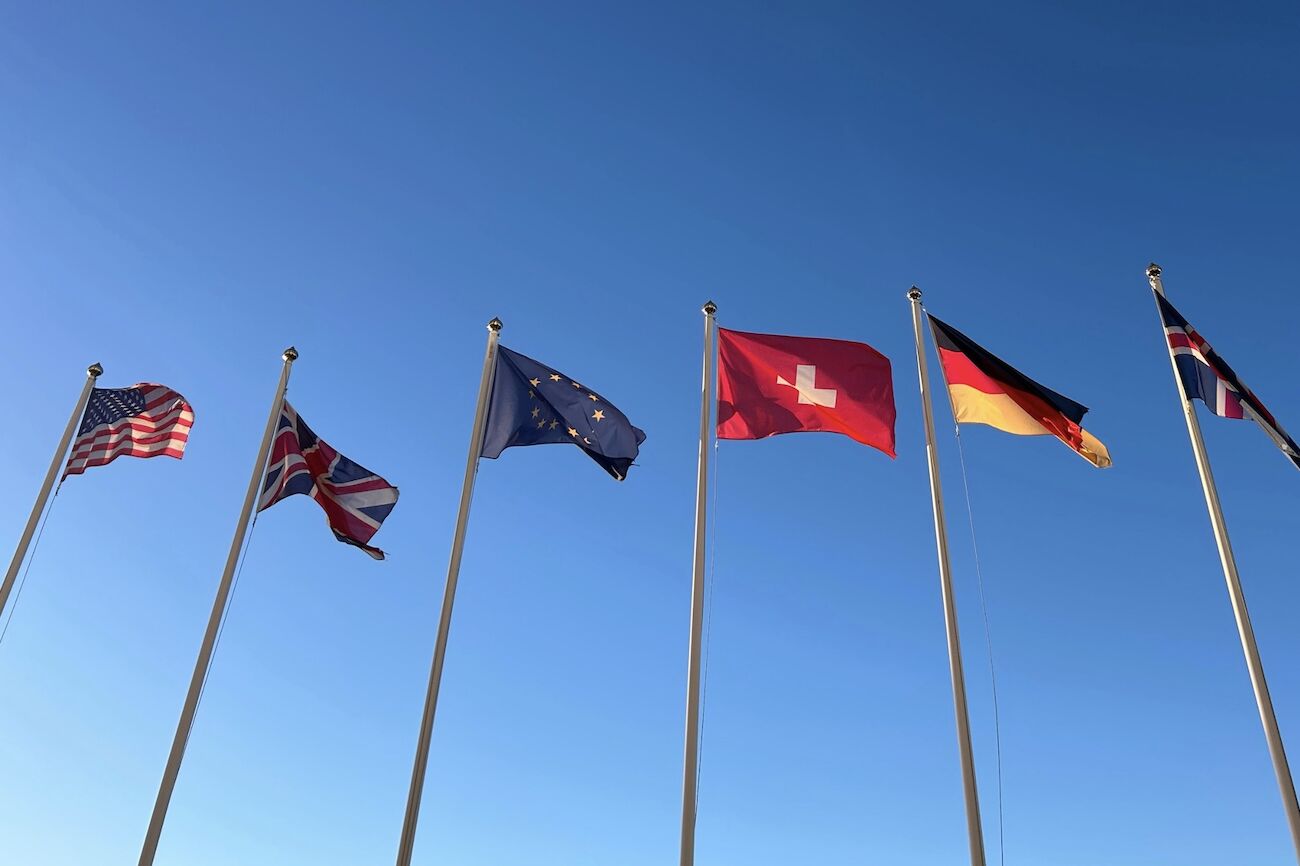 Fünf nordische Länderflaggen auf Masten vor einem bewölkten Himmel.