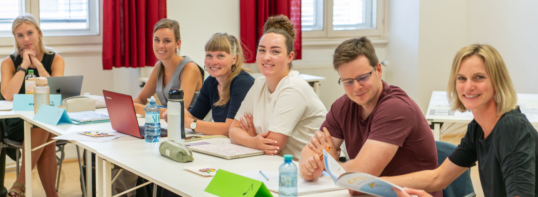 Frauen sitzen im Publikum, lächeln und klatschen während einer Veranstaltung.