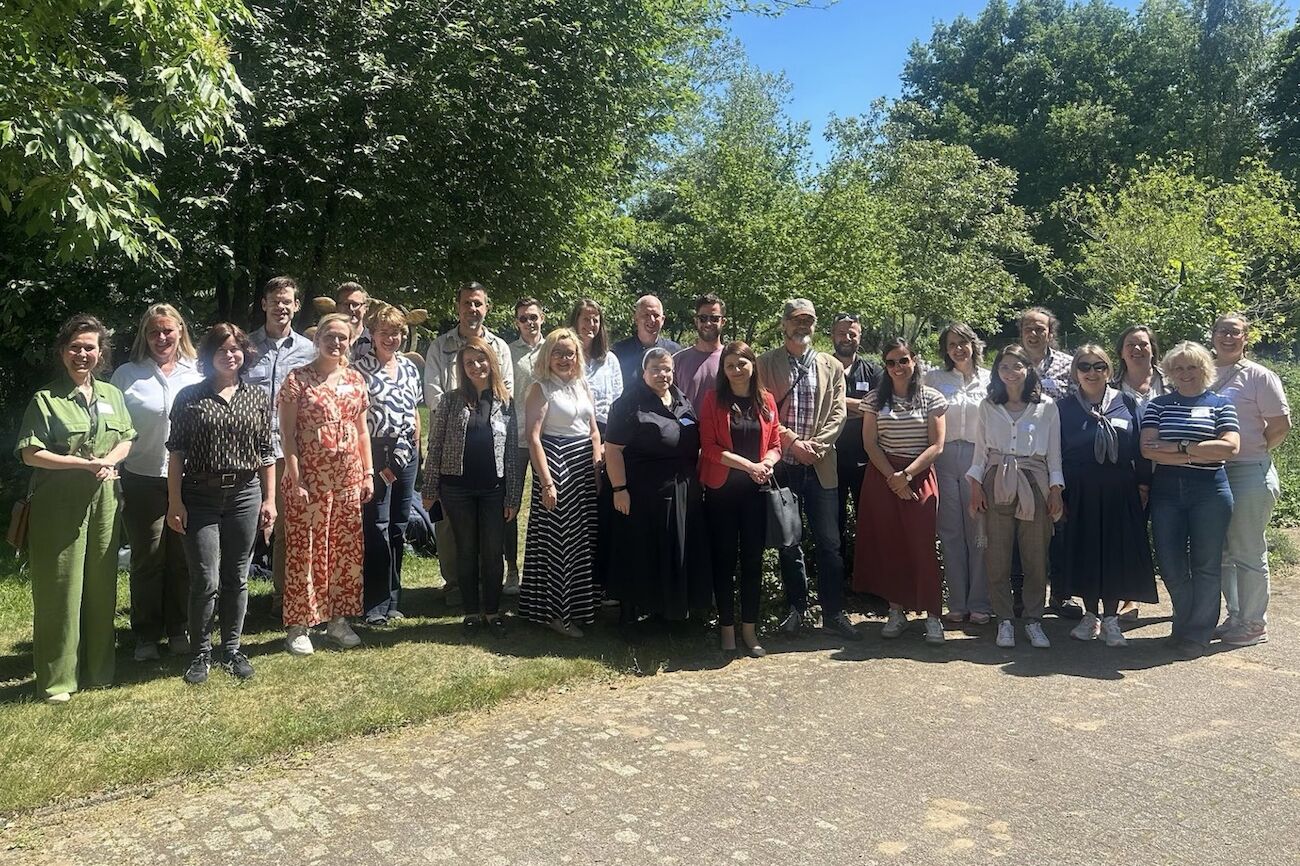 Eine Gruppe von Menschen steht an einem sonnigen Tag im Freien zusammen und posiert für ein Foto.