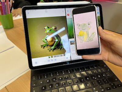 Auf einem Tablet ist ein Froschfoto zu sehen, auf einem Telefon die Kinderzeichnung eines Frosches.