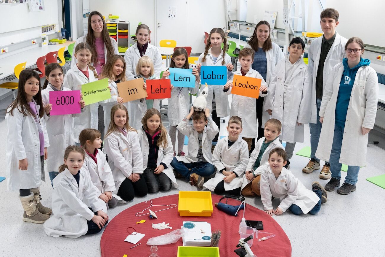Gruppenbild Kinder und Lehrende in weißen Labormänteln
