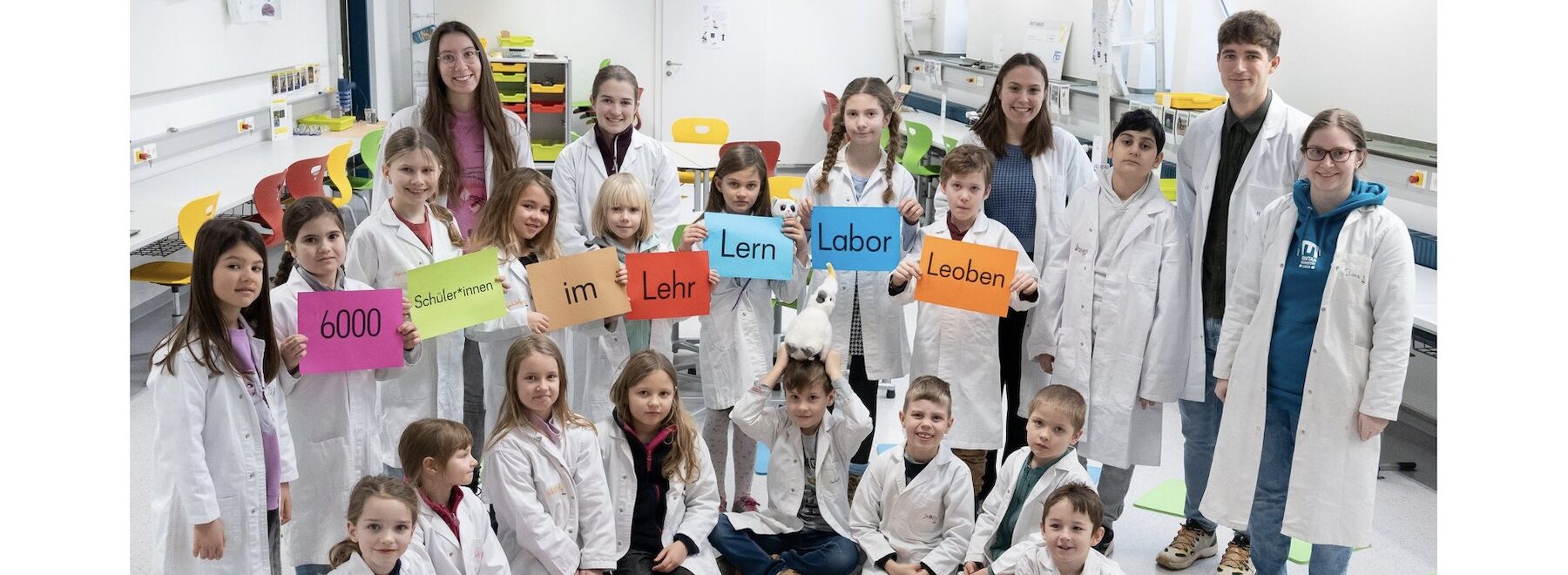 Gruppenbild Kinder und Lehrende in weißen Labormänteln