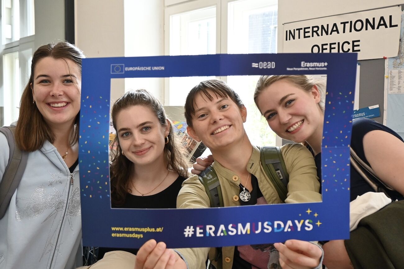 Vier Studierende blicken durch ein Erasmus-Papierfenster hindurch