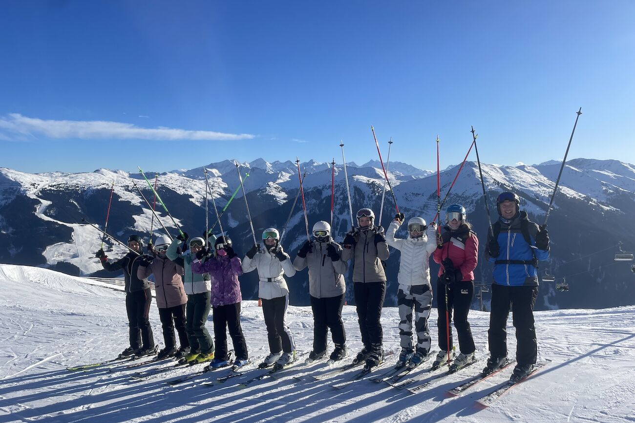 Gruppenbild Skifahrer*innen mit Lehrendem auf der Skipiste