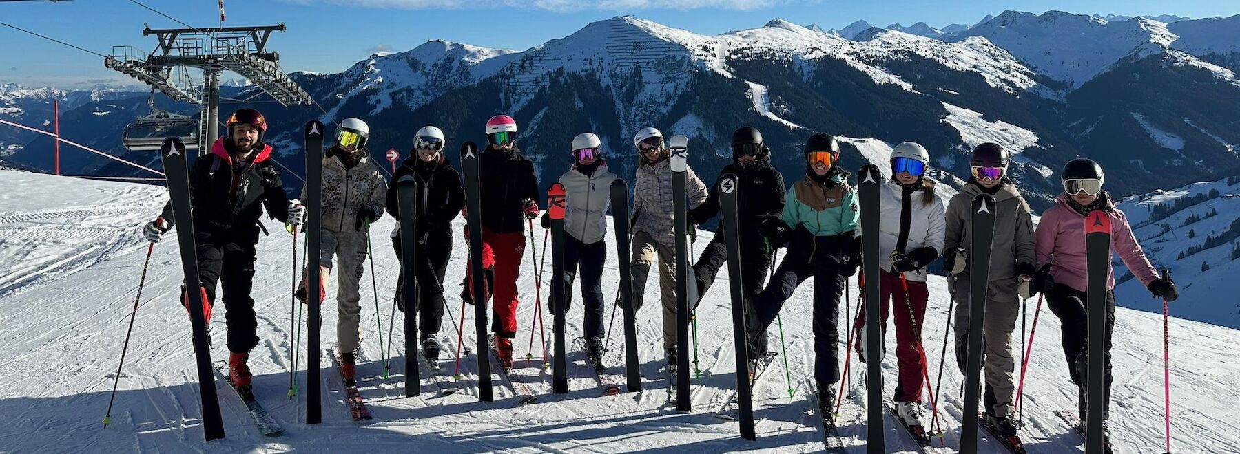 Gruppenbild Skifahrer*innen mit Lehrendem auf der Skipiste
