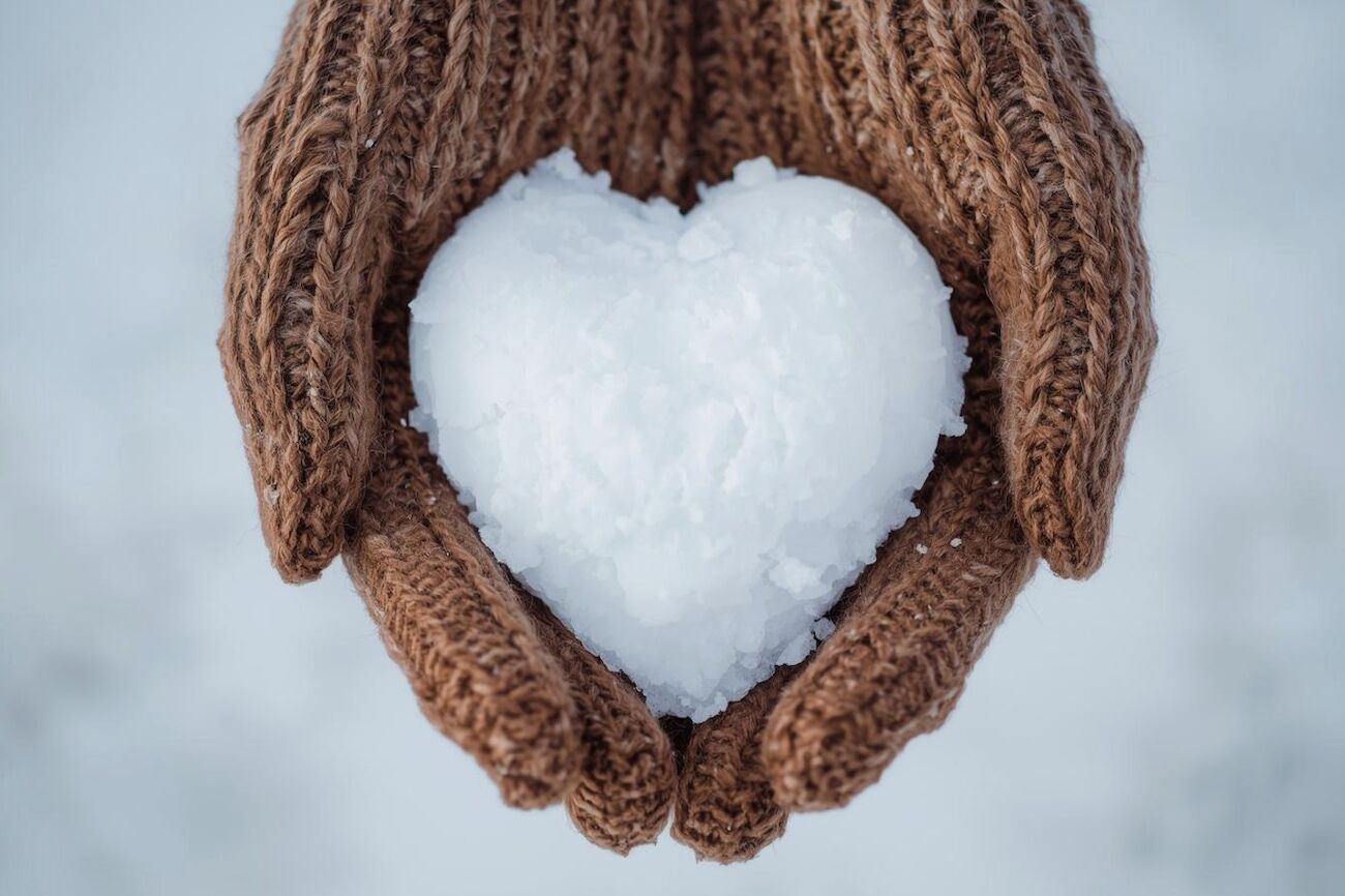 Eine Hand mit Handschuhen hält einen Schneeball.