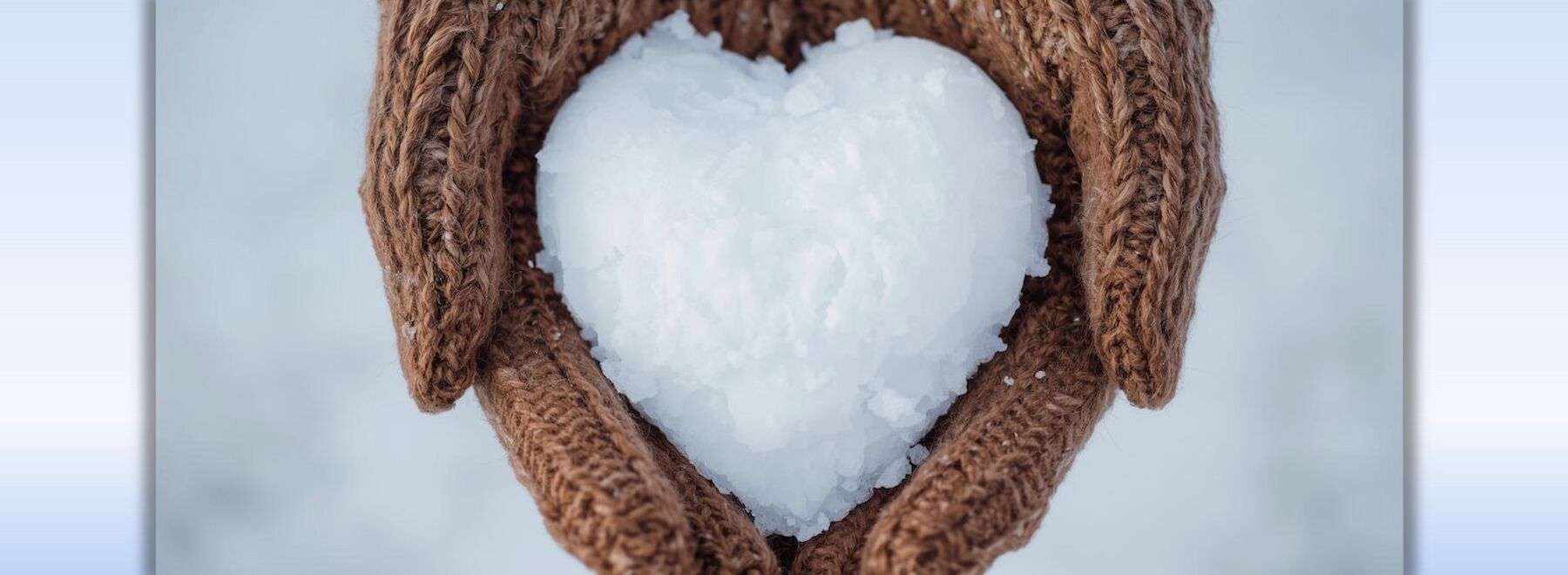 Eine Hand mit Handschuhen hält einen Schneeball.