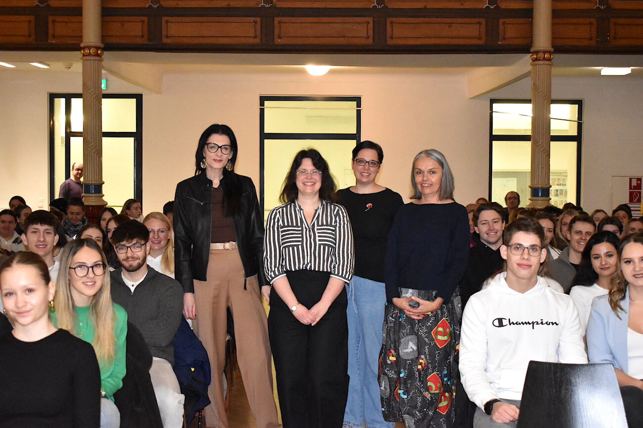 Gruppenbild der Organisatorinnen inmitten sitzender Studierender im Festsaal